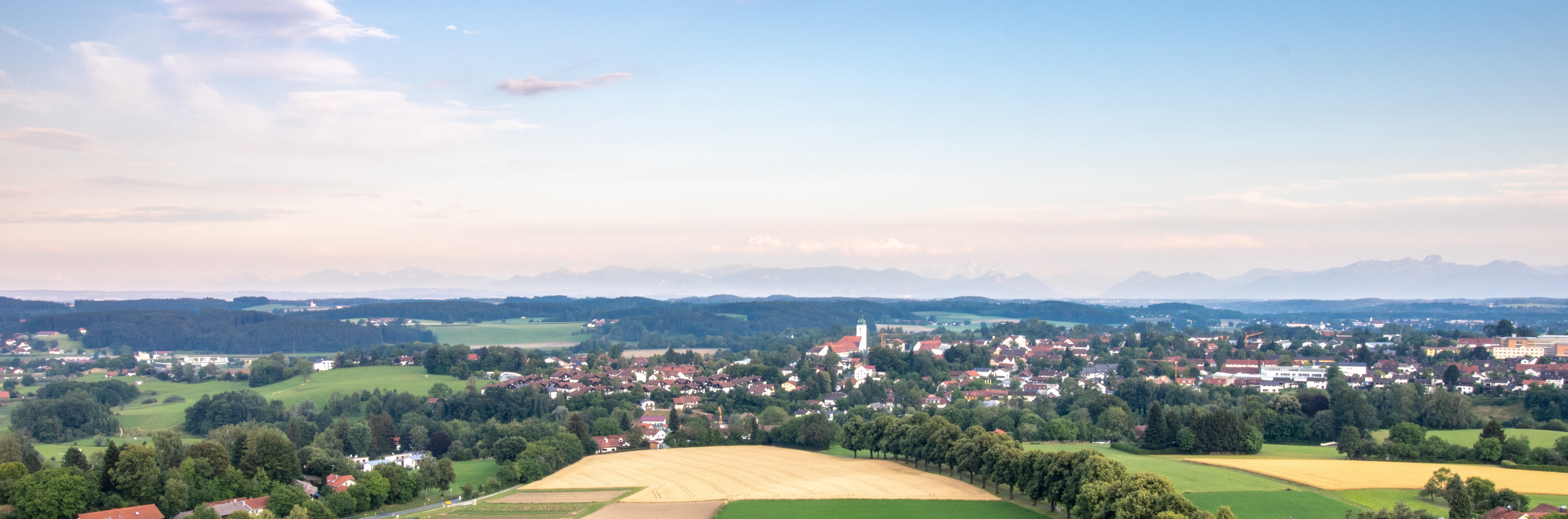 Felder und eine Stadt von oben mit Bergen im Hintergrund.
