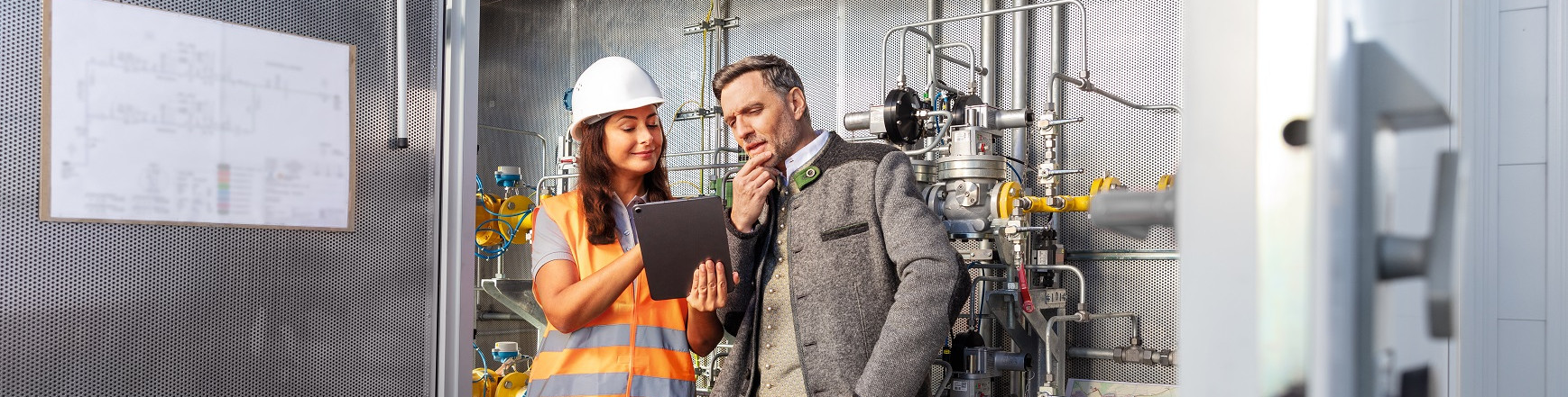 Ein Mann und eine Frau schauen in einer Gas-Druckregel- und Messanlage auf ein Tablet.