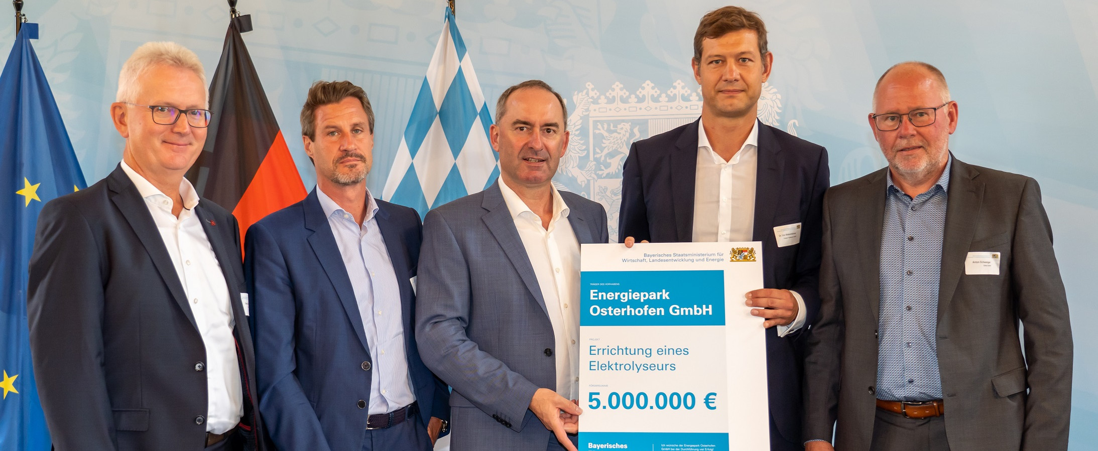 Fünf Männer bei der Übergabe des Schecks für ein Elektrolyseurprojekt.