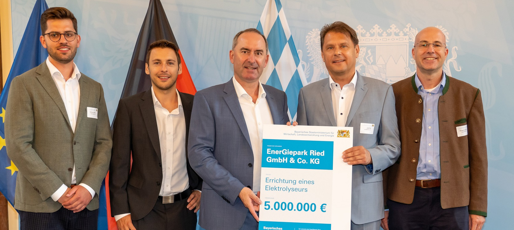 Fünf Männer bei der Übergabe des Schecks für ein Elektrolyseurprojekt.