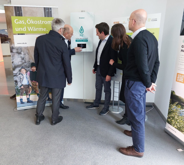 Fünf Personen schauen sich eine 100%-Wasserstofftherme in der ESB-Zentrale an