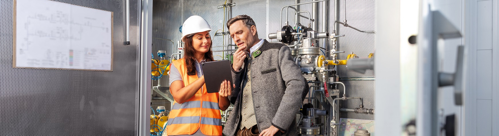 Ein Mann und eine Frau schauen in einer Gas-Druckregel- und Messanlage auf ein Tablet.