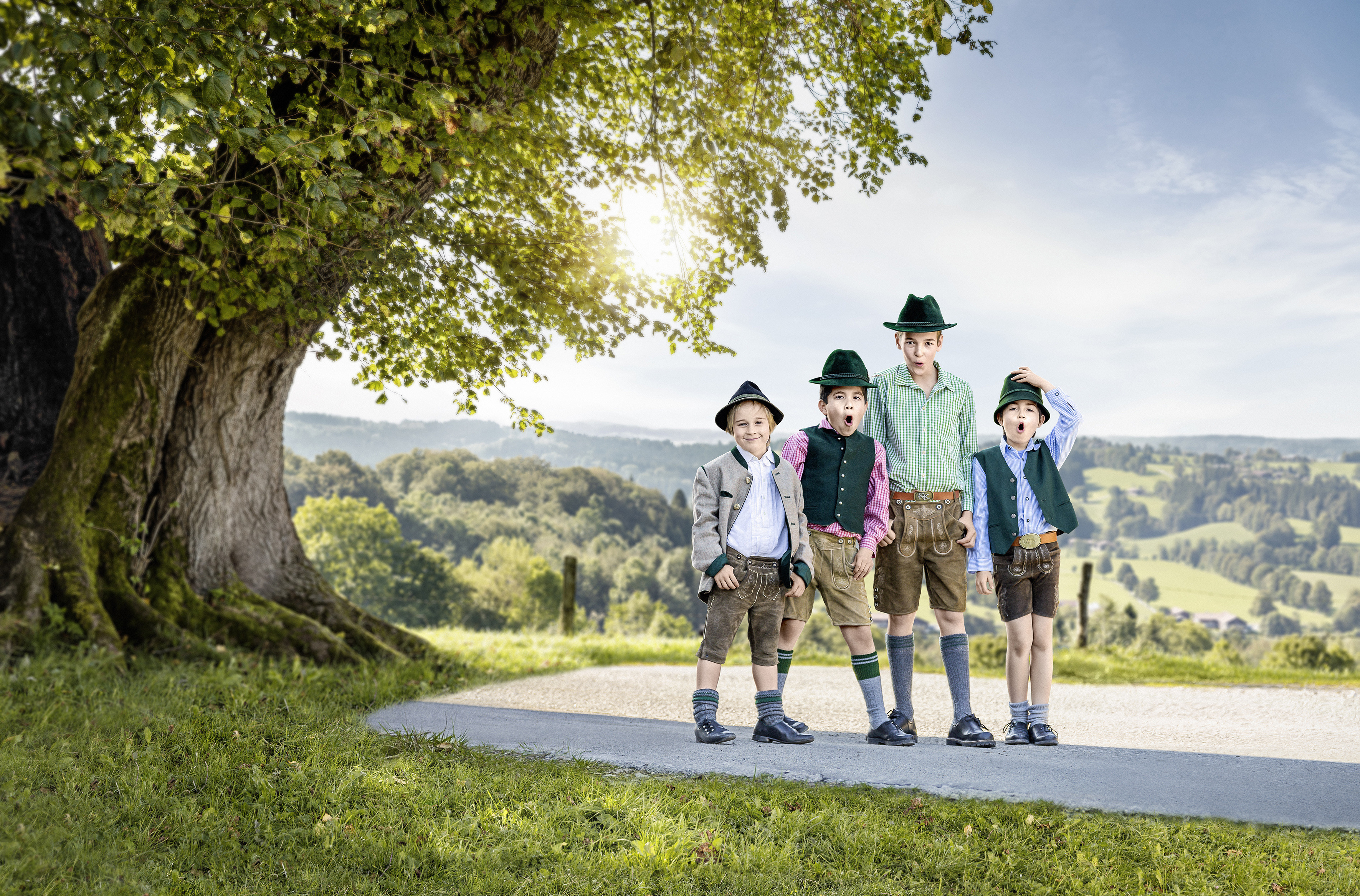 Vier Jungen in Lederhosen stehen unter einem Baum.