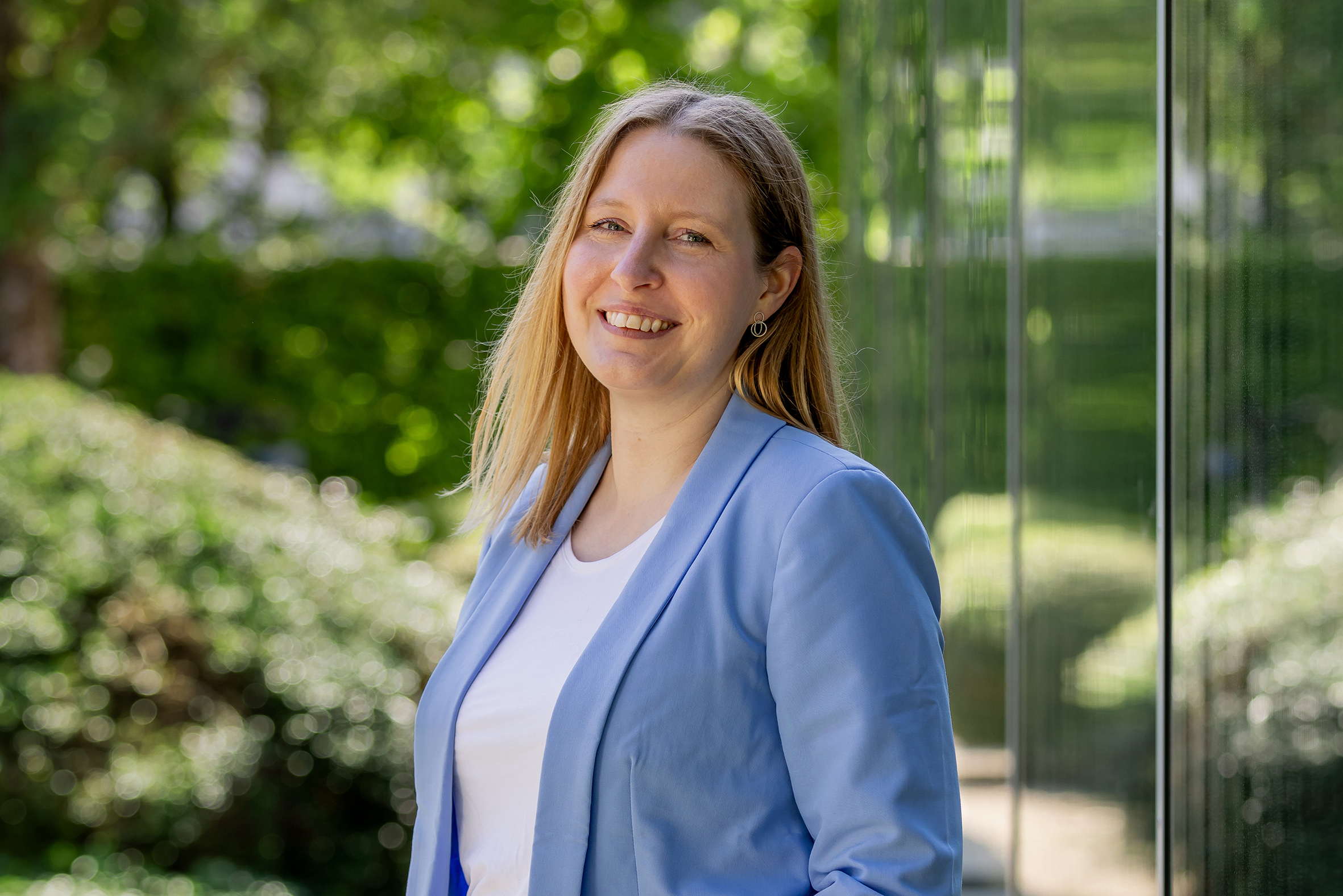 ESB Mitarbeiterin vor Glasfenster mit Bäumen im Hintergrund